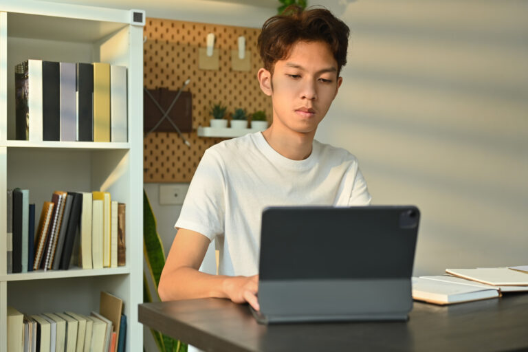 Young asian male looking at digital tablet, working or doing res