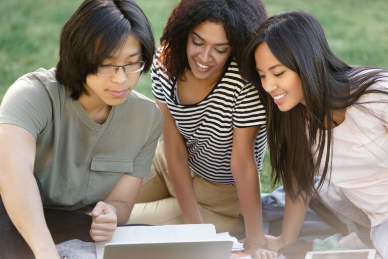 International students collaborating on a laptop to create a professional LinkedIn profile for U.S. internships