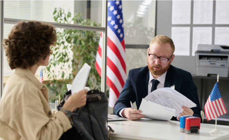 U.S. visa interview at embassy desk; officer examines paperwork amid F-1 and J-1 visa duration rule 2025 changes.
